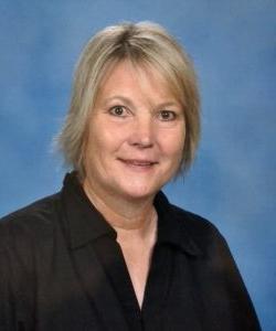 Mature woman smiling for a portrait against a blue backdrop at Howard Payne University. | HPU